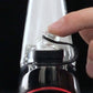 Hand operating glass carb cap on black dab rig against black backdrop